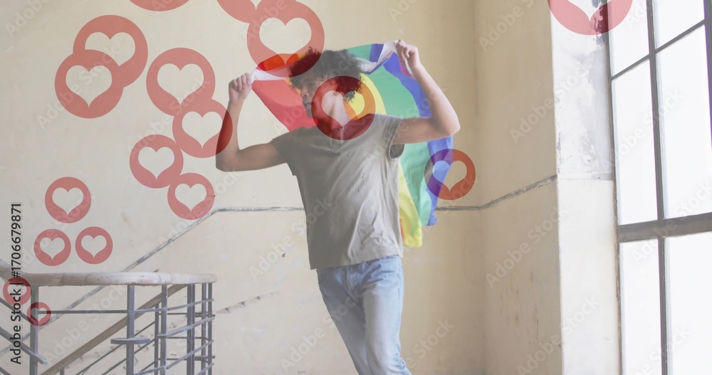 Fototapeta premium Man holding rainbow pride flag above head on staircase landing, with railing, floating heart icons