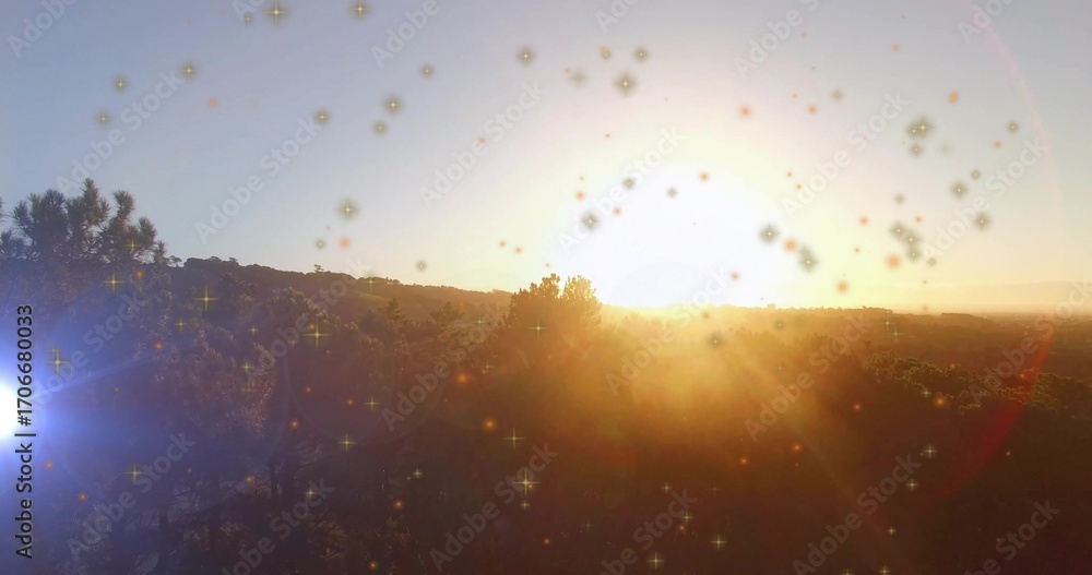 Fototapeta premium Casting glowing sun illuminating scrubby trees, rolling hills at hillside, with lens flare sparkles