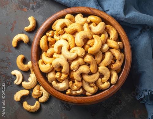 Roasted cashew nuts in wooden bowl with pile of cashew nuts on the table. top view.