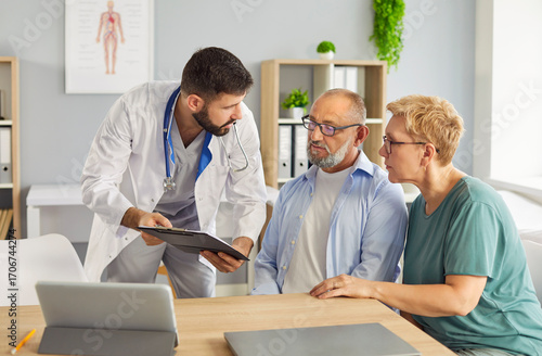Fotografie Family doctor explains care plans to elderly patient and companion during medical consultation, discussing diagnosis