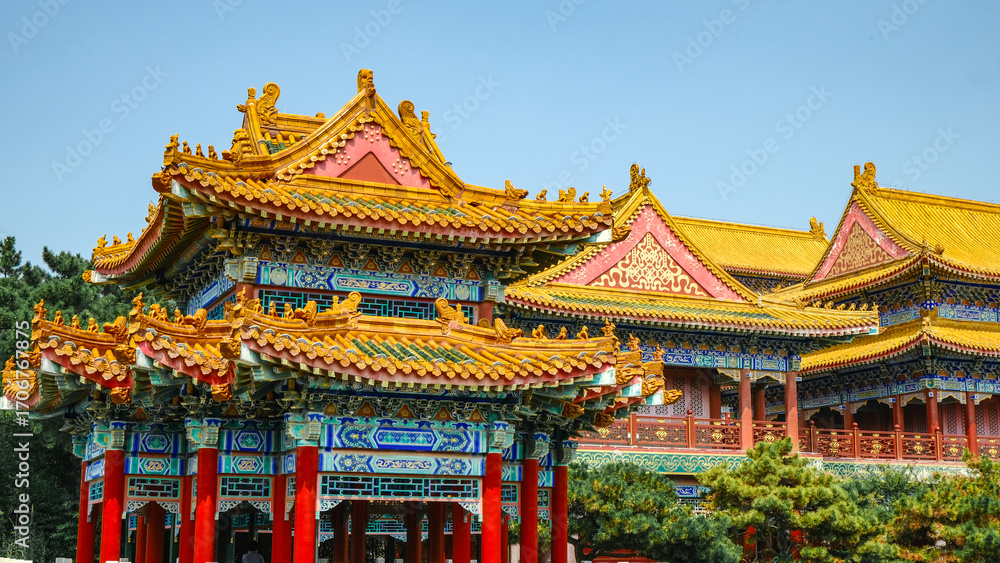 Fototapeta premium Traditional Chinese temple in Penglai, Shandong, with red pillars, golden roofs, and ornate details, surrounded by lush greenery and a serene natural setting.