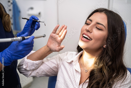 Young woman afraid of the dentist, rejects dentist with hand gesture. 