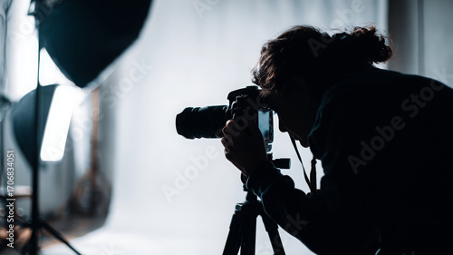 Professional photographer adjusting camera in studio setting, focused on capturing perfect shot