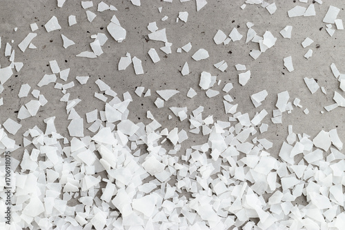 Close-up of magnesium flakes on gray concrete background, salt crystalline texture. Natural White sea salt as wellness or spa products for bath or relaxation, self-care or sustainable living