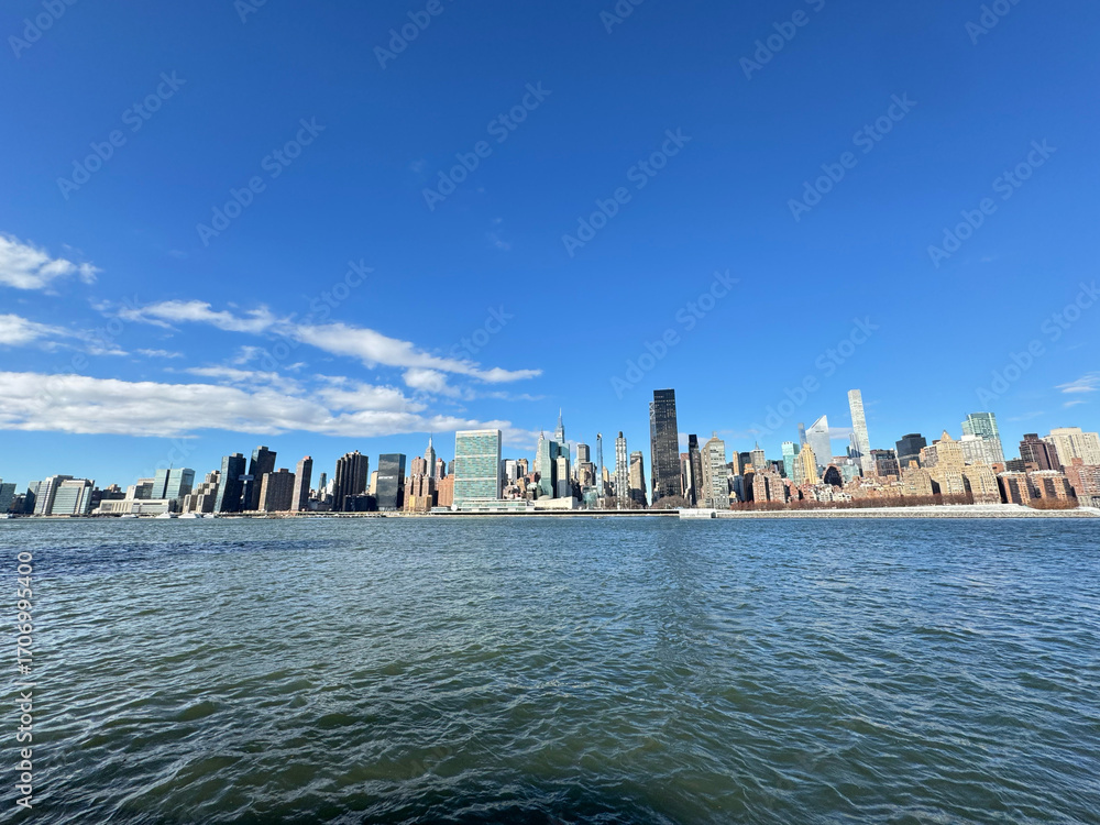 Fototapeta premium View of NY Manhattan skyscrapers across the East River. United Nations Headquarters, Trump World Tower, etc.Wide. From Gantry Plaza State Park in Long Island City.