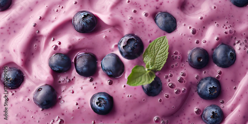 Close-up of fresh blueberries in creamy purple blueberry smoothie with mint garnish, healthy fruit yogurt texture background