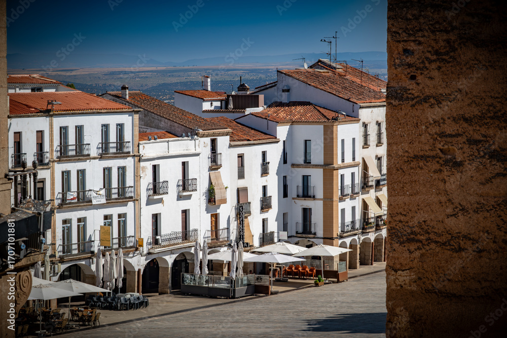 Obraz premium Vista panorámica del casco histórico de la ciudad española de Cáceres con vistas a los tejados de tejas marrones de edificios antiguos alrededor de la plaza principal en el soleado día de verano