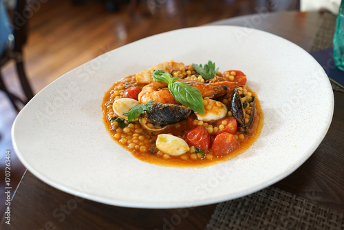 Close up plate of Fregola Pasta with seafood in red sauce- Italian cuisine