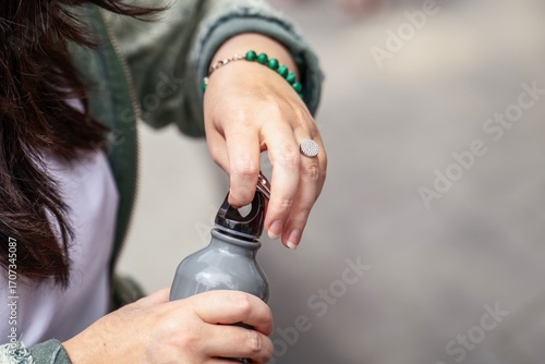 Wallpaper Mural woman's hand trying to unscrew a plastic cap from a grey metal water bottle on a neutral background Torontodigital.ca