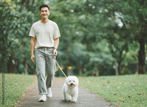 Smiling man walking with white dog in green park