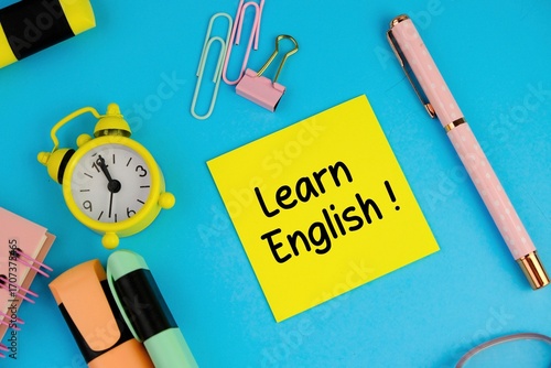 Word LEARN ENGLISH made with carved letters on blue desk with office or school supplies, stationery. Concept of English language courses