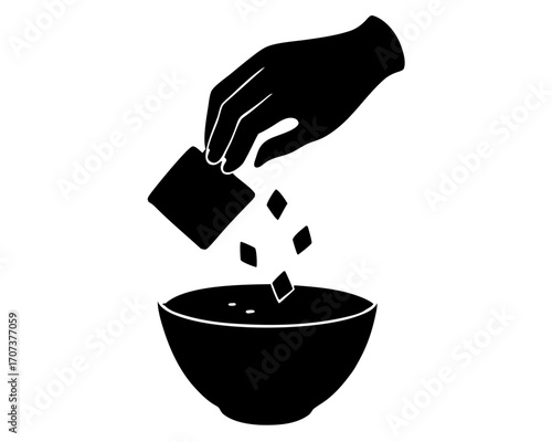 Hand pouring small cubes into a bowl