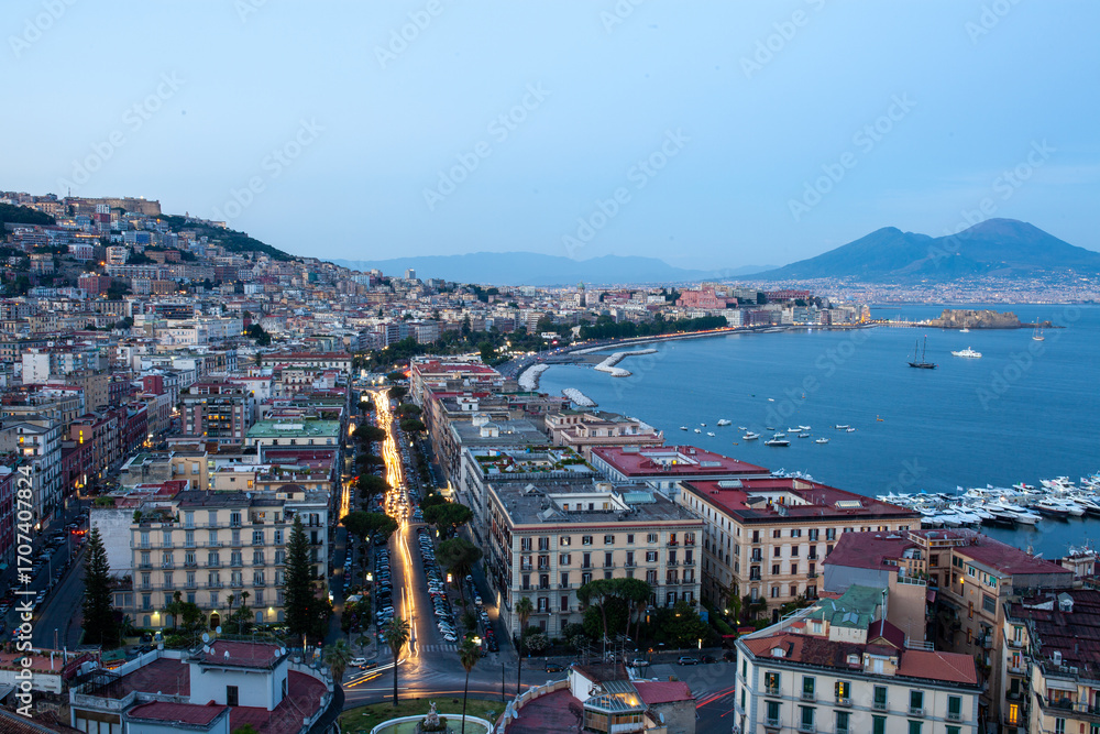 Obraz premium Naples waterfront cityscape depicting urban density coastal panorama usable in travel promo or architectural lighting design, illustrating sunset ambiance over Mediterranean harbour in low light