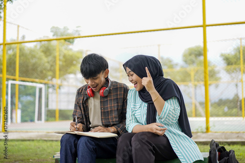 фотографія A moment of inspiration between two diverse Asian college students studying outdoors