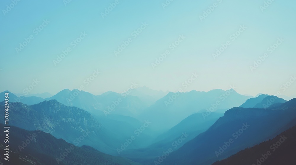 Obraz premium Panoramic view of distant mountain ranges, soft blue tones, hazy atmosphere