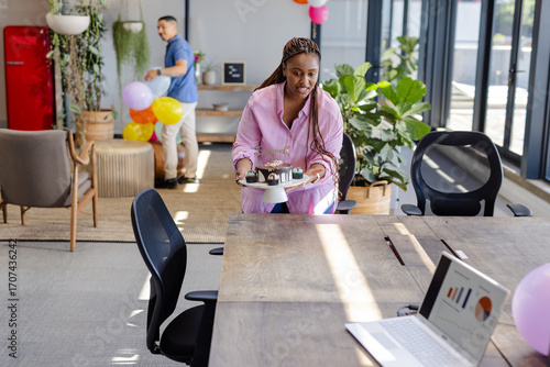 Woman in office carrying cake platter, preparing for business celebration