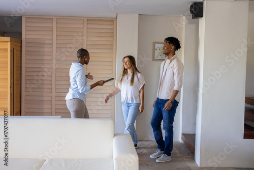 Real estate agent showing mixed friends around modern apartment, discussing features
