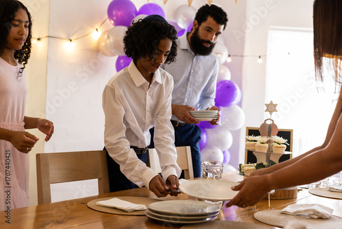 Family setting table for bar mitzvah with festive decorations and cupcakes