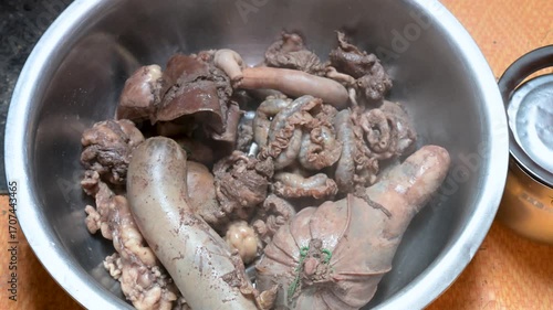 A steaming bowl of freshly cooked sheep offal, a traditional nomadic meal. A close-up on nose-to-tail cuisine, featuring liver, intestines, and meat-filled stomach.