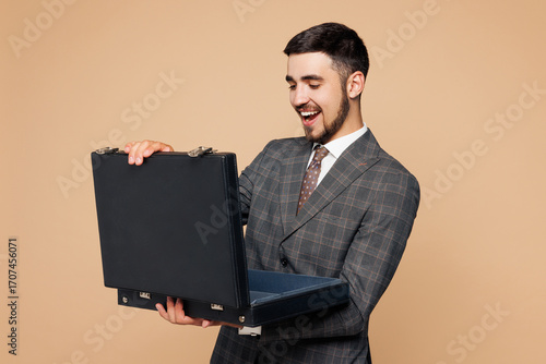 Quadro em tela Young successful employee business man corporate lawyer he wear classic formal grey suit shirt tie work in office hold in hand open black briefcase isolated on plain beige background studio portrait