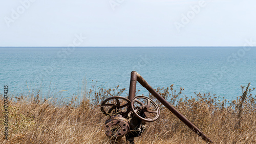 Rusty industrial valve by the sea coast with dry grass