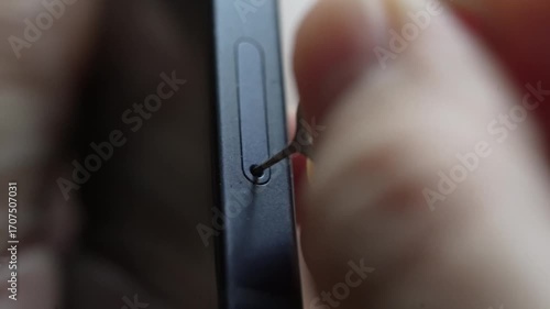 Person taking out and inserting a sim card into back of mobile phone. Sim card in tray being inserted into phone, closeup