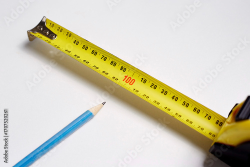 Measuring tape and pencil lie on a white background
