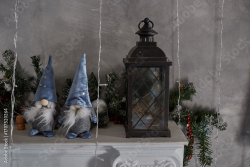 Two dwarf toys in caps on Christmas Eve evening stand on the fireplace