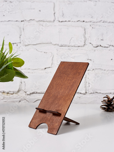 Brown wooden phone holder, on a white table