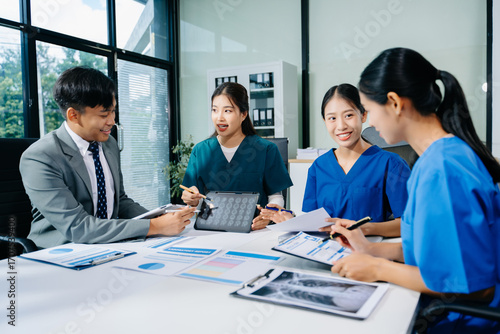 Doctors, nurses, and consultant review anatomy data on tablet and lab reports in a modern clinic. Healthtech, diagnostics, teamwork, and medical collaboration.
