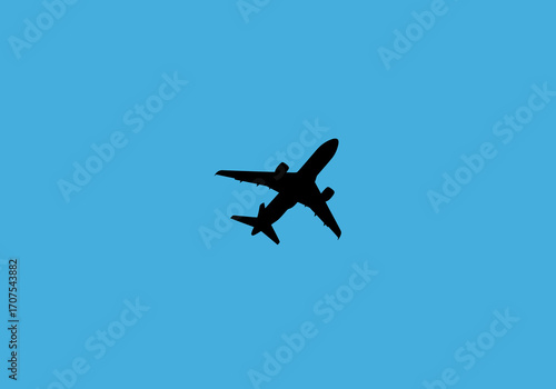 An airplane silhouette flying in a clear blue sky
