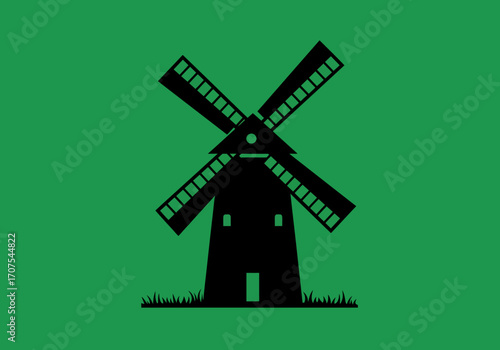Black windmill silhouette on green blades angled set on grass