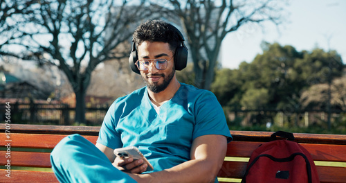 Man, medical student and headphones with phone for streaming, listening to music and schedule. Male person, intern doctor and mobile for online podcast, radio subscription and healthcare residency