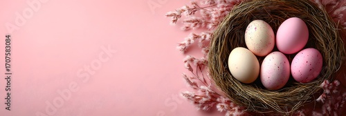 Colorful Easter eggs in a nest on a soft pink background during springtime