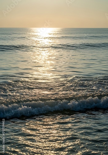 Golden sunlight glints on tranquil ocean waves, creating a serene and peaceful scene at sunrise or sunset.