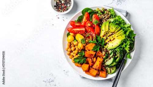 Colorful, healthy bowl with quinoa, roasted sweet potato, chickpeas, avocado, tomatoes, and greens