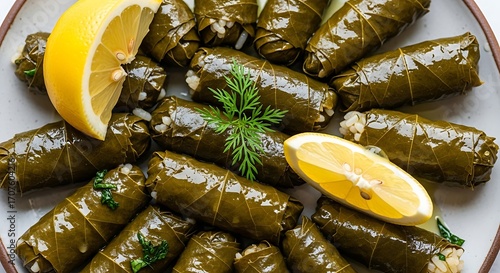 Deliciously prepared grape leaves, filled with rice and herbs, arranged attractively on a plate with a lemon wedge.