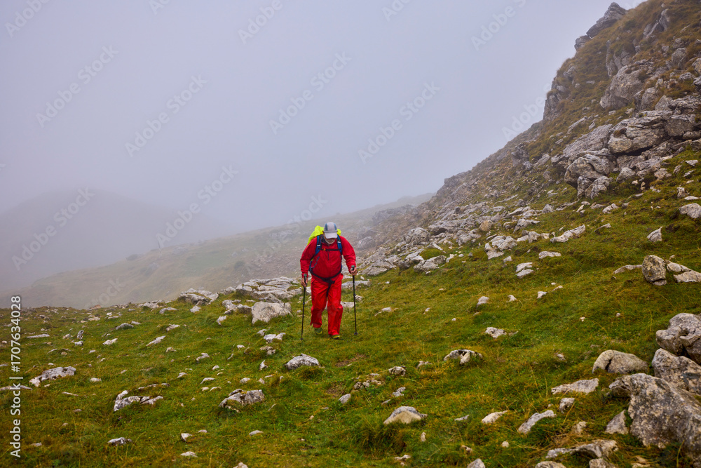 Obraz premium a strong old man climbing a mountain on a cloudy day