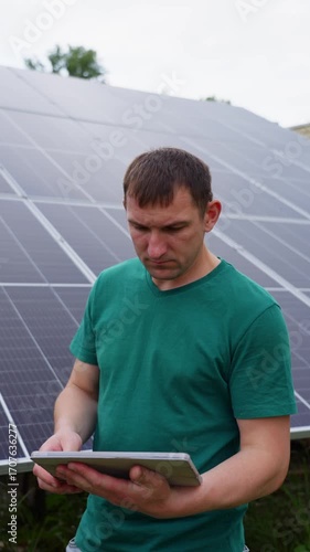 Man with tablet controls solar panel system at power plant renewable energy technology supporting ecology environmental care and green electricity innovation. High quality 4k footage