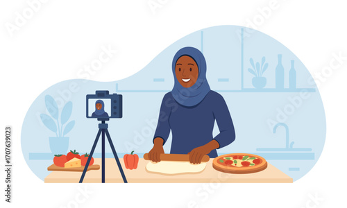 Woman recording food vlog with camera in home kitchen. Muslim vlogger in hijab live streaming cooking pizza recipe. Content, social media posts creation. Video tutorial, culinary show