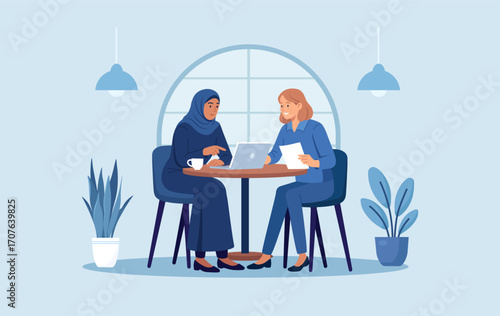 Muslim woman and her european friend are discussing project in cafe. Business consultation and deal talk. Diversity partnership. Diverse women working or studying together in co-working space