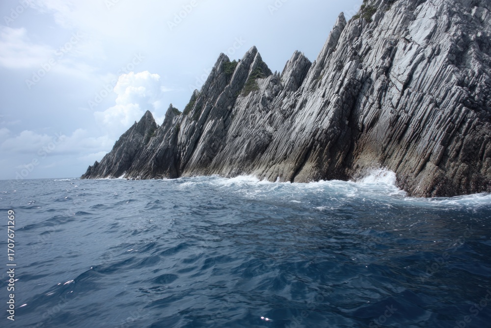 Naklejka premium Dramatic coastal scenery showcasing a rugged shoreline with layered rock formations meeting the ocean waves.