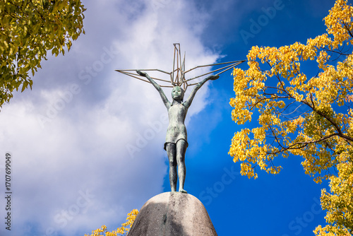 Peace Statue of Sadako Sasaki Holding Paper Crane in Autumn Foliage at Hiroshima Peace Memorial Park, Japan
