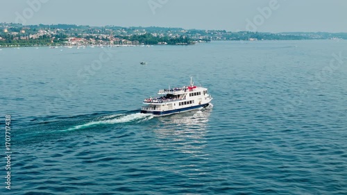 Passenger ferry crossing Lake Garda between towns, aerial. Public transport service providing intertown lake transit on a scheduled route