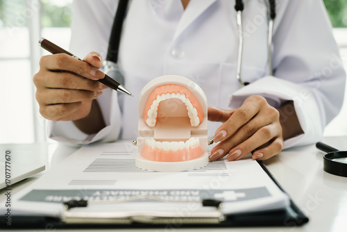 A dentist holds a dental model, demonstrating oral health, teeth structure, hygiene, and dental care for patient education and treatment guidance.