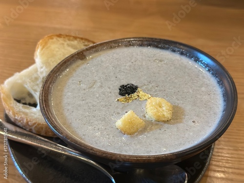 A meticulously presented bowl of rich, creamy Truffle Mushroom Soup, garnished with truffle bits and croutons, perfectly arranged with toasted bread, ready to be enjoyed.