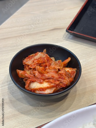 Traditional Fermented Korean Food: Two Vertical Images of Vibrant, Spicy Napa Cabbage Kimchi (Baechu Kimchi) Side Dish, Served in a Dark Black Bowl on Wood.