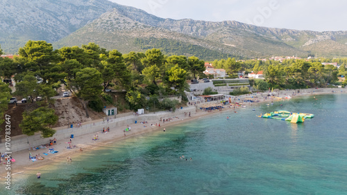Fototapeta Naklejka Na Ścianę i Meble -  A beach with a lot of people and a few green inflatables