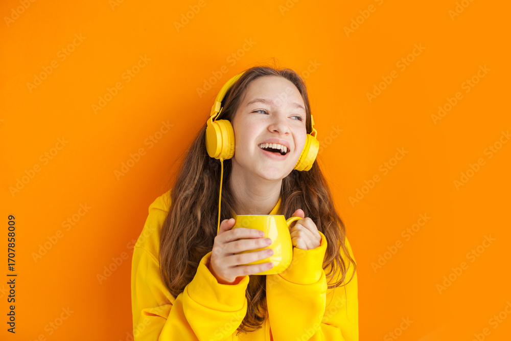 Fototapeta premium Cheerful young woman girl in yellow hoody posing isolated on yellow wall background