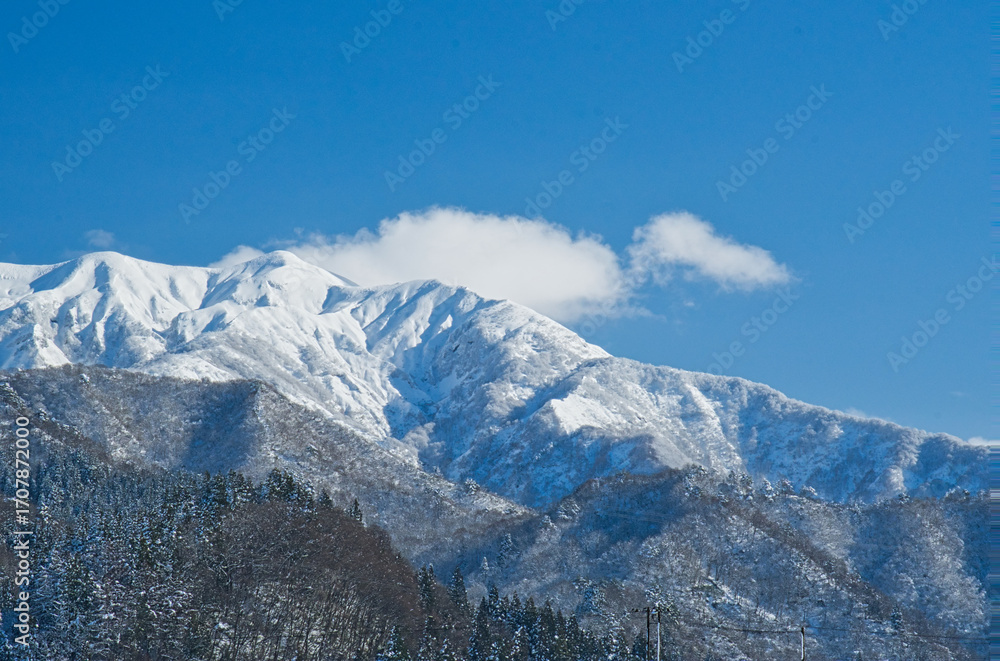 Obraz premium 青空の下、白い雲をまとう雪化粧した粟ヶ岳の雄大な姿